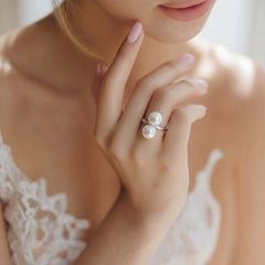 Close-up of a woman's hand wearing a white double pearl sterling silver ring with a slightly blurred background