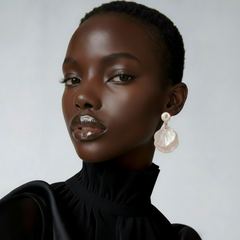 Woman wearing white mother‑of‑pearl double shell dangle earrings with gold‑tone metal accents plain background.