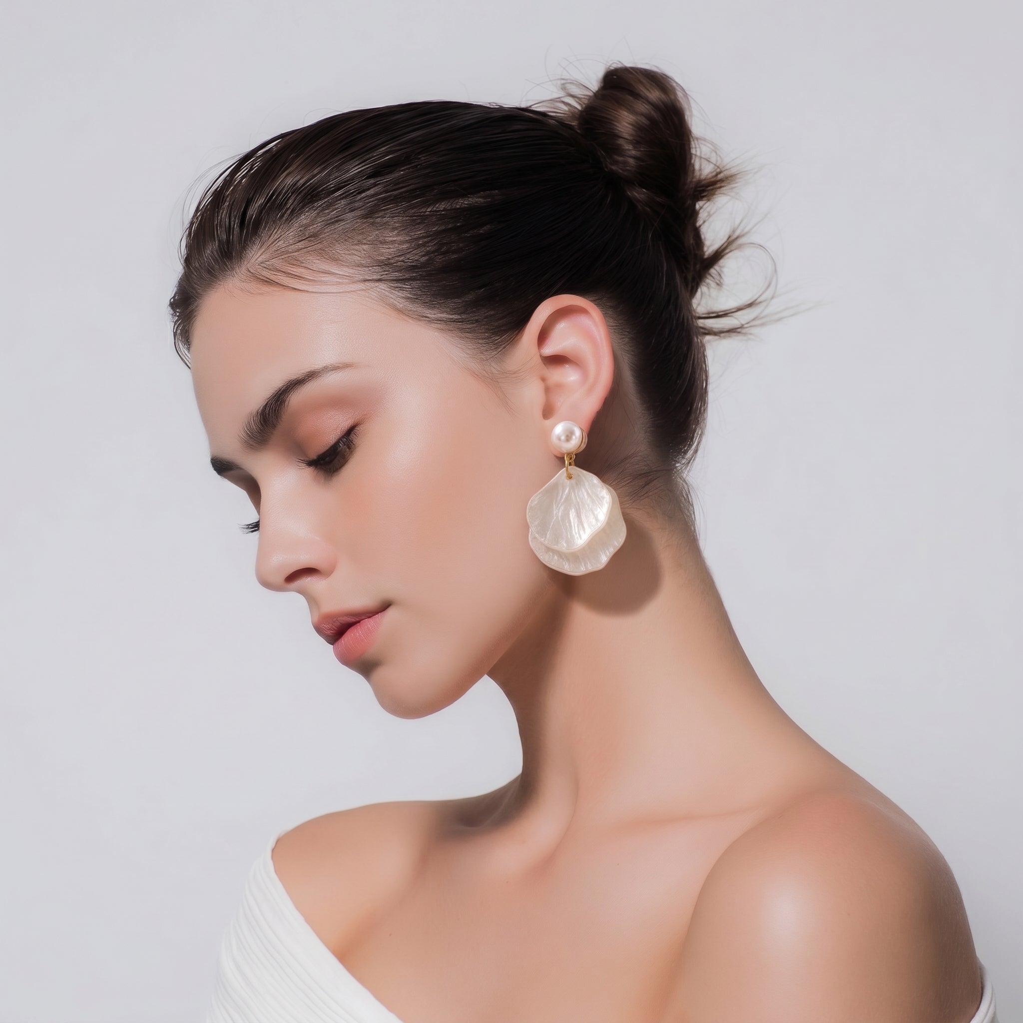 Woman wearing large shell earrings against a plain background