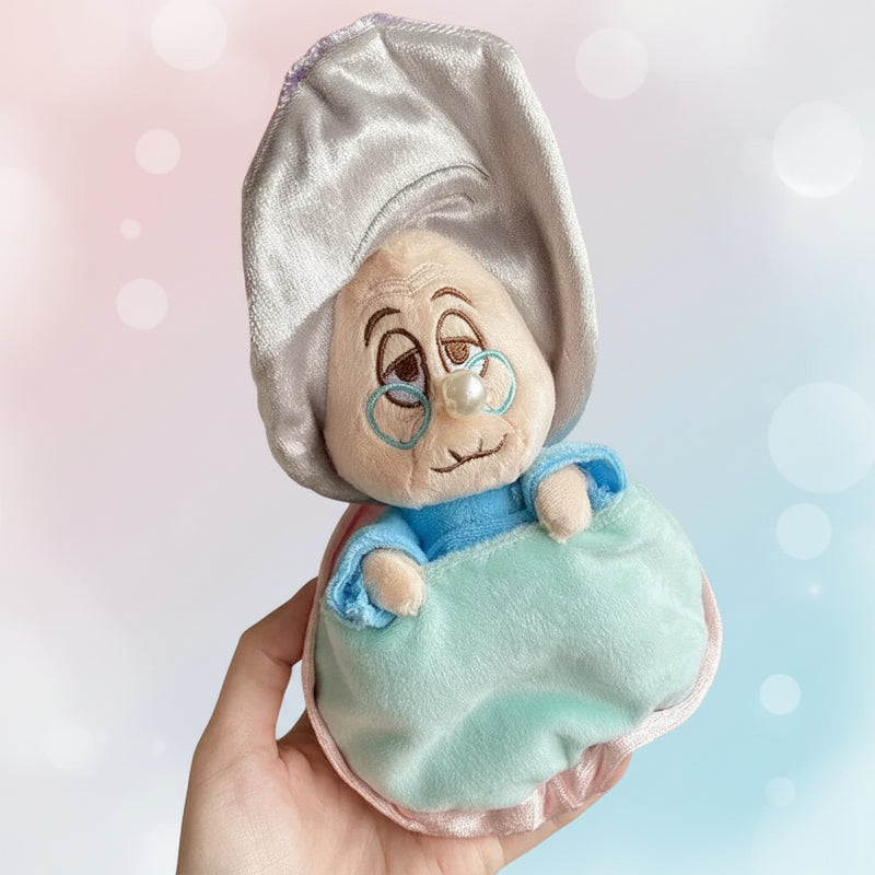 Soft pastel Pearlz Kids Baby Oyster Grandma plush pendant with embroidered face, silver hood, and pearl‑style charm held in hand.
