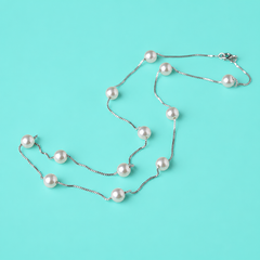 Sterling silver station necklace with evenly spaced micro‑pearls displayed on a soft aqua background.